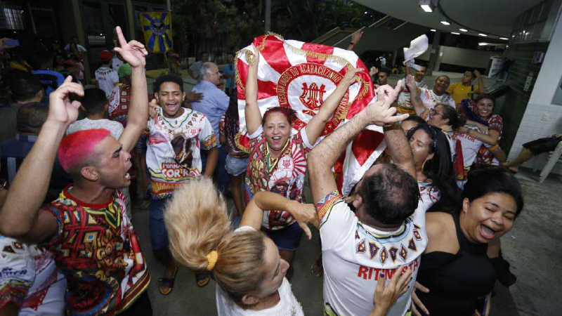 pessoas pulando e comemorando levantando bandeira da escola de samba unidos do acaracuzinho